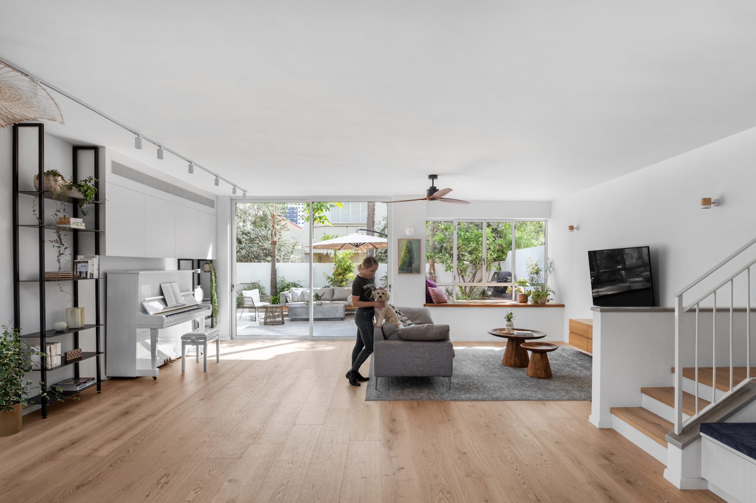 Open-plan space with a black bookcase and white stairs