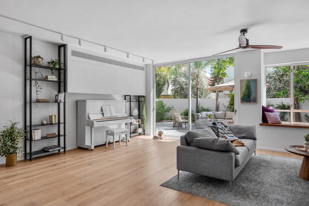 Living room with a piano, a grey sofa and glass doors to the yard