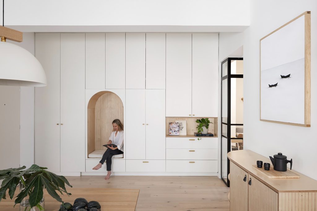 White cabinet wall with an arched seat niche and a black glass door