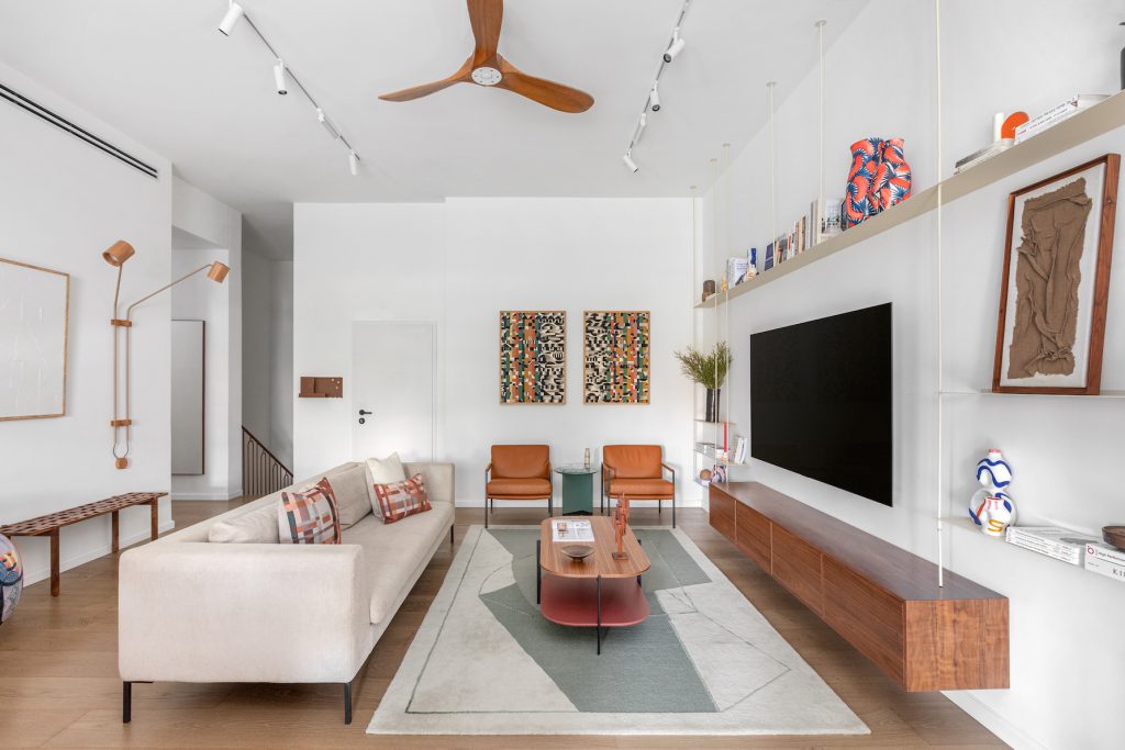 White living room with a light sofa, a floating wooden TV unit and two artworks