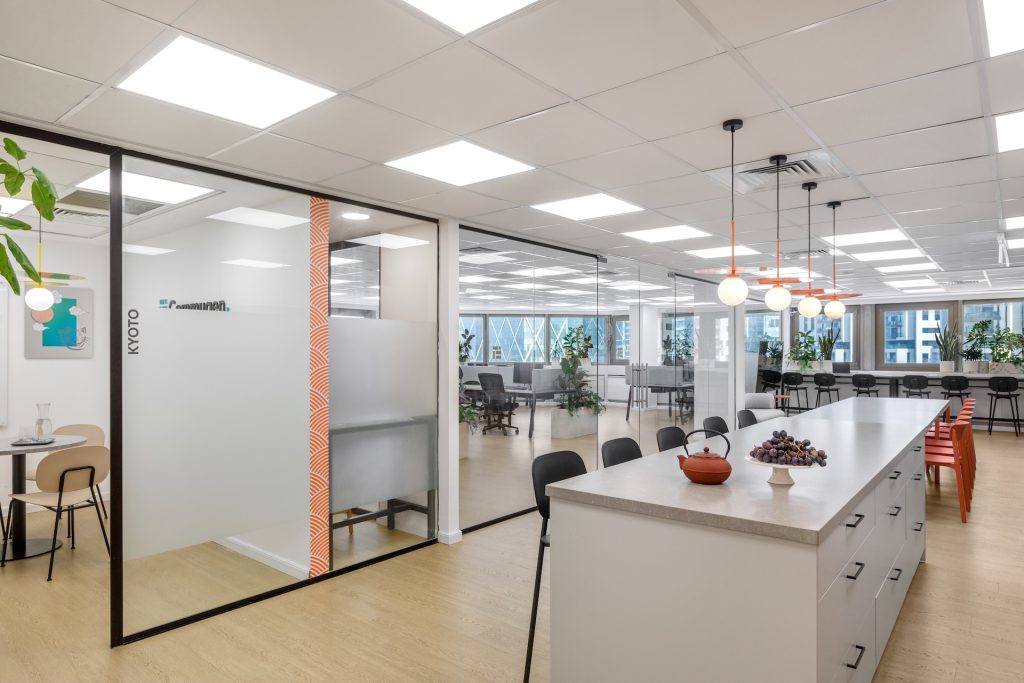 Office kitchen island beside a glass meeting room
