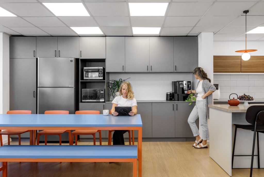 Blue table with orange benches facing a grey kitchen