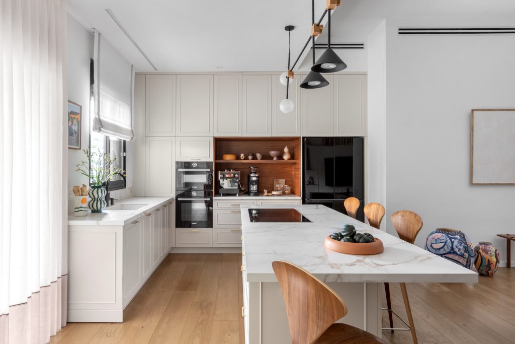 Marble kitchen island with a built-in hob and a wooden niche in the cabinet wall