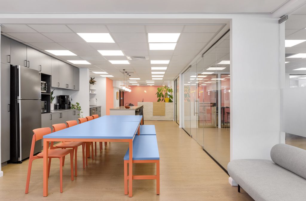 Long blue dining table with orange chairs in the kitchenette