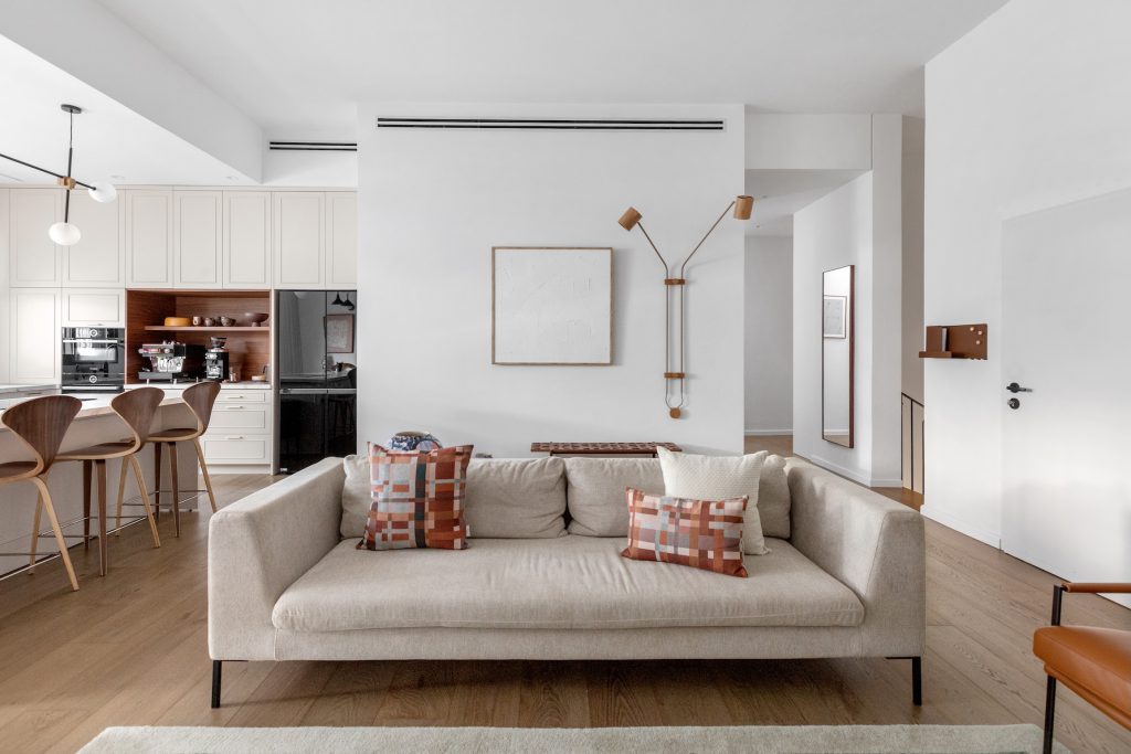 Light sofa with terracotta cushions and a brass wall lamp