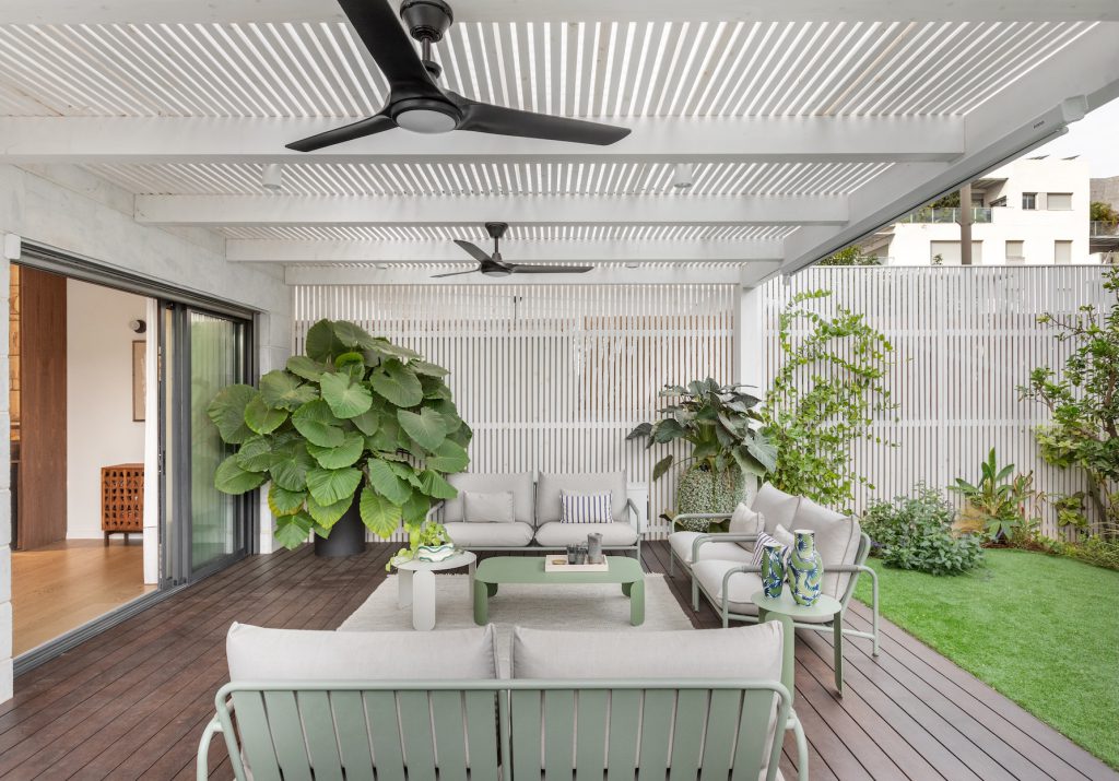 Covered terrace with a white pergola, timber deck and tropical plants