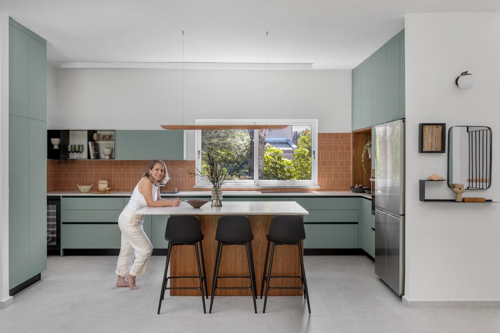 Sage-green kitchen with a terracotta backsplash and a wooden island