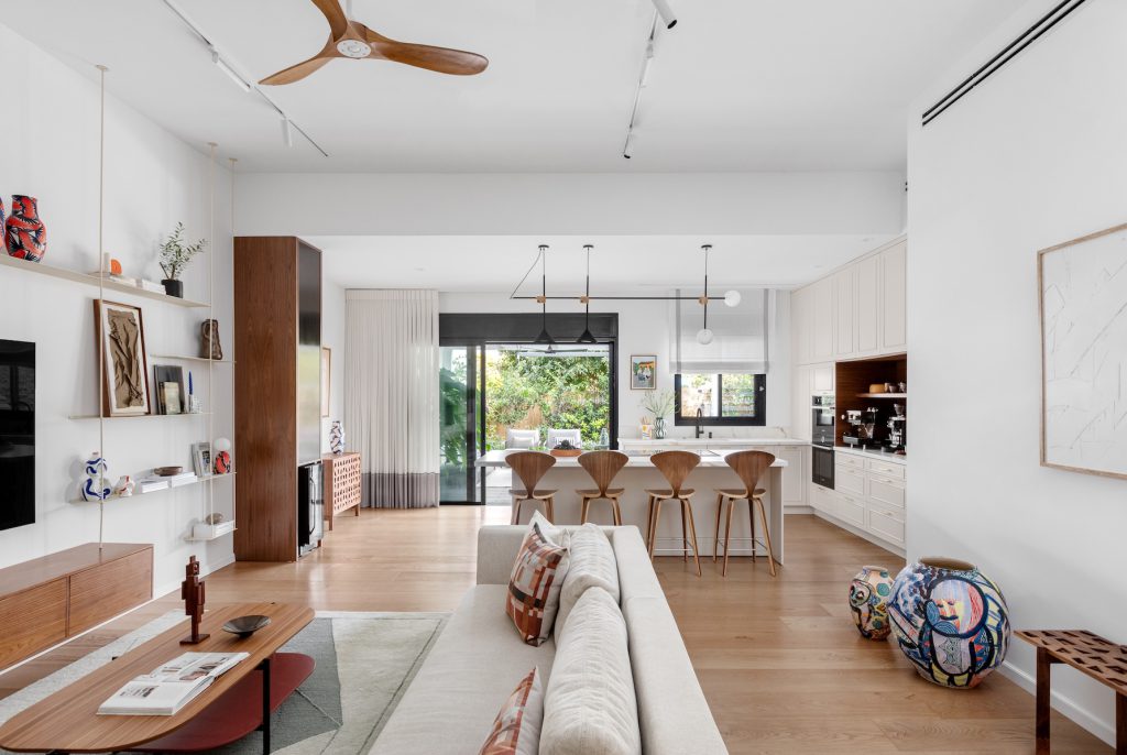 Open-plan space: light sofa, open shelving and a dining area facing the garden
