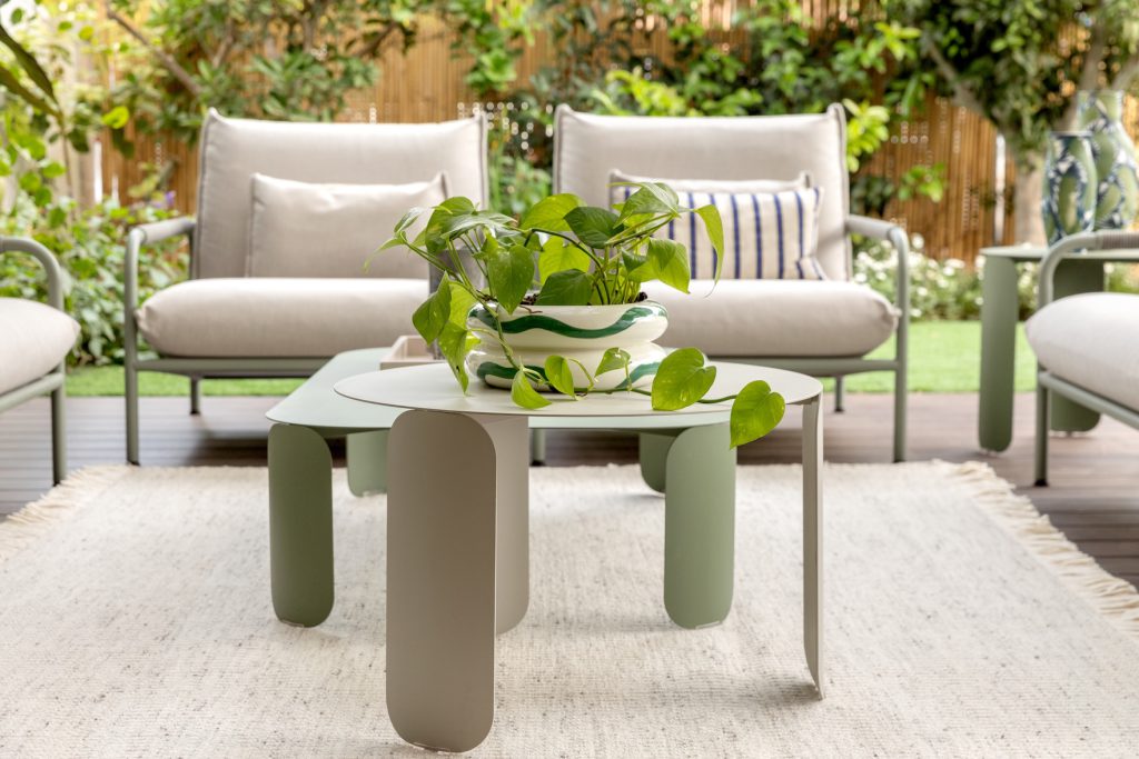 Outdoor armchairs and a sage-green coffee table facing the garden