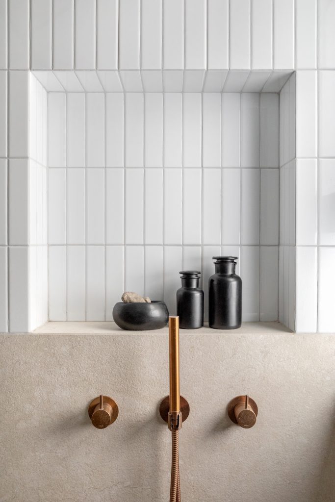 Shower niche with white tiles and copper-tone taps