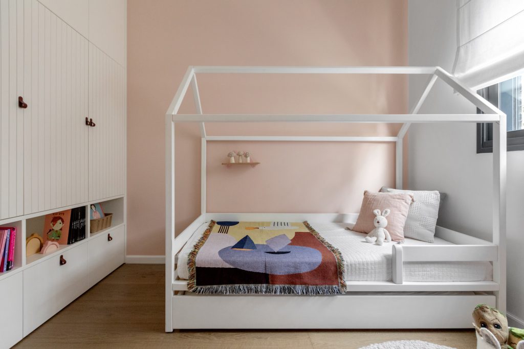Pink girl's room with a white house-frame bed and built-in wardrobe