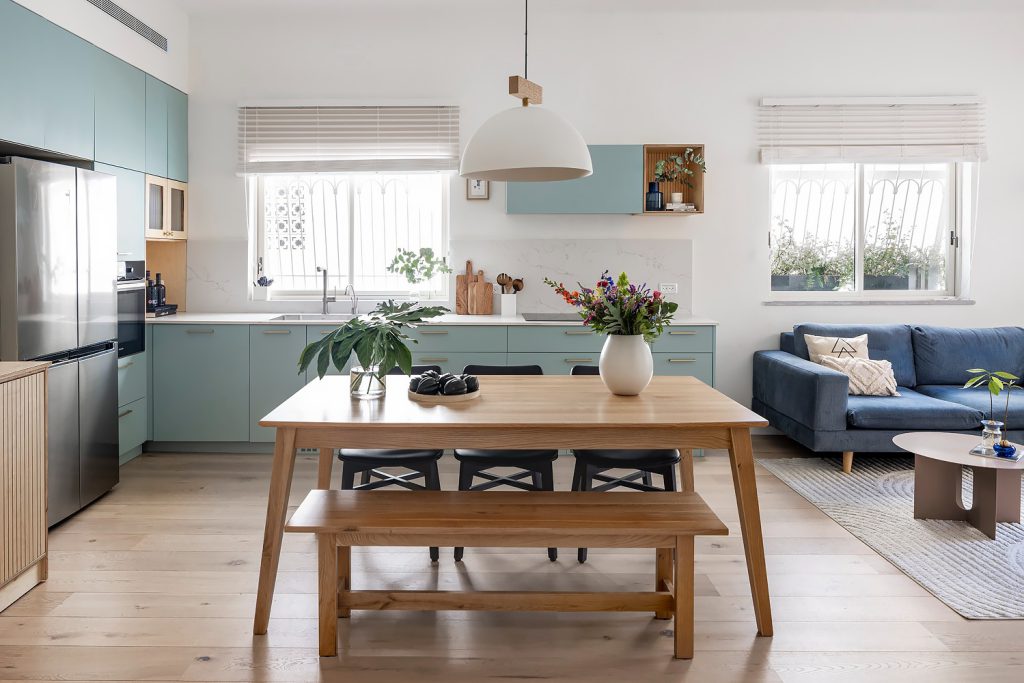 Pale blue kitchen, dining area and blue sofa in one space