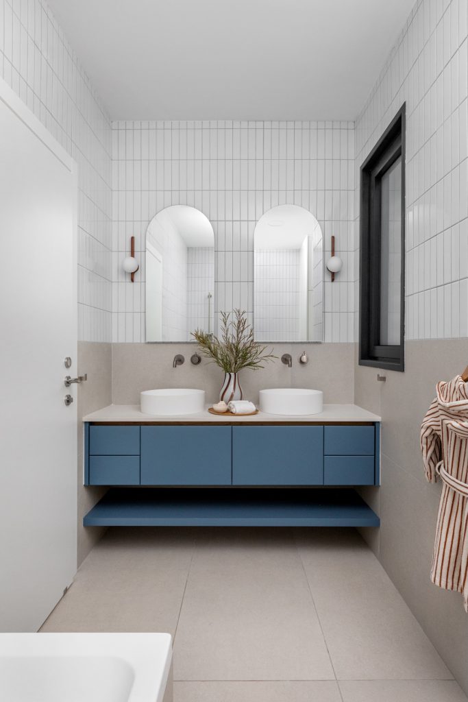 Bathroom with a blue double vanity and two arched mirrors