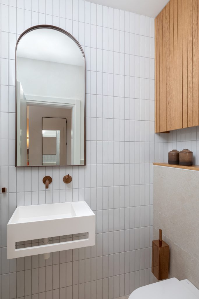 Guest toilet with a white wall-hung basin and an arched mirror