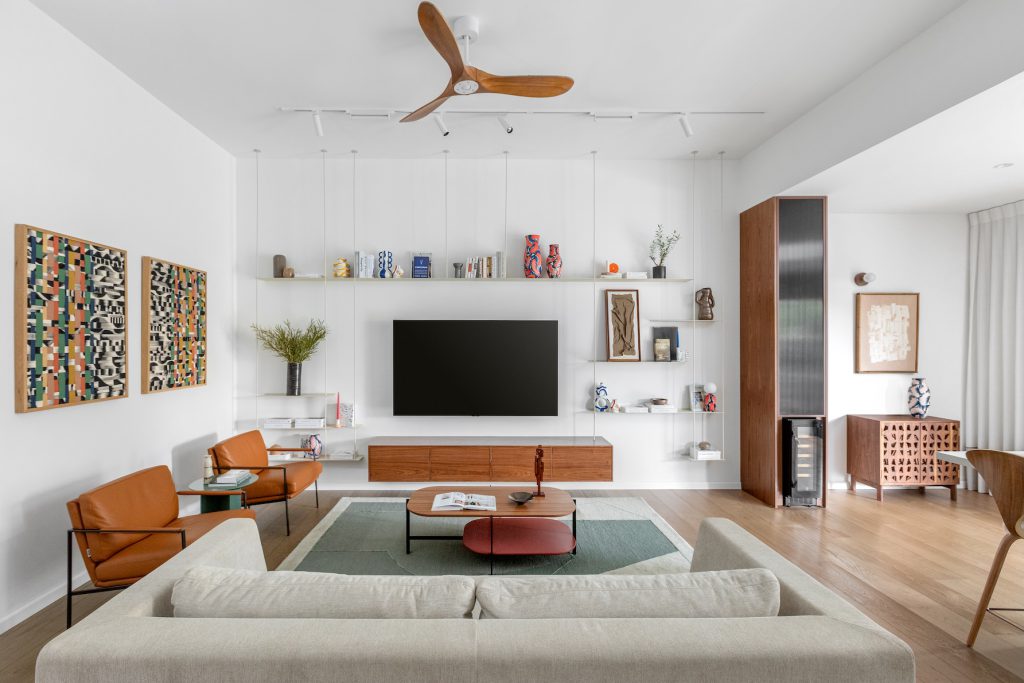TV wall with white floating shelves and a walnut console