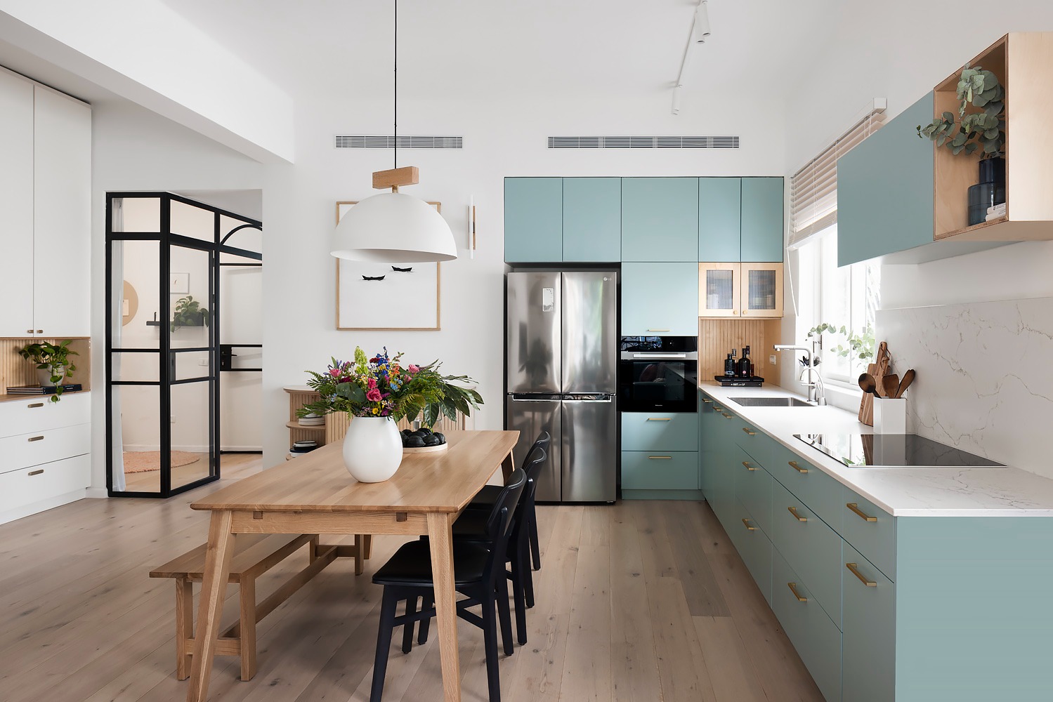 Pale blue kitchen with a wooden dining table and bench