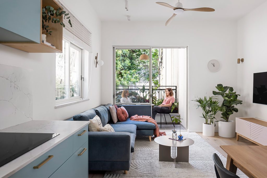 Living room with a blue sofa facing a leafy balcony