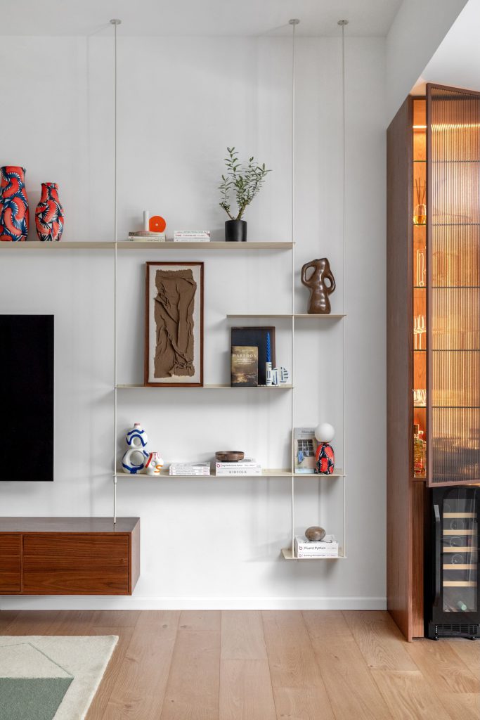 Floating shelves with ceramics next to a wooden wine cabinet