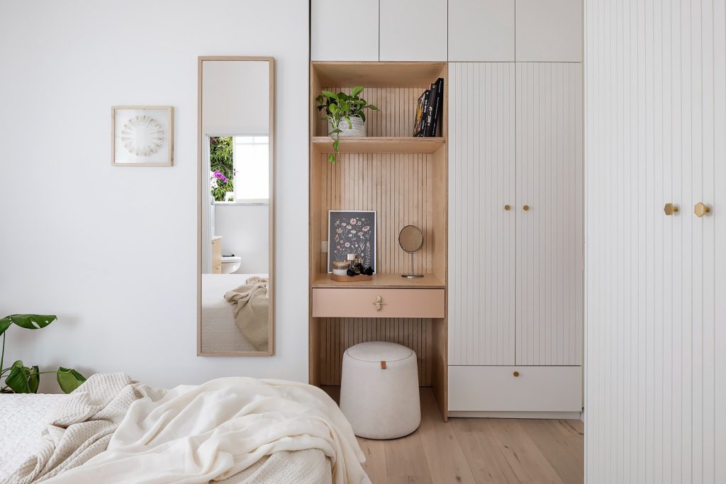Bedroom with a wooden dressing nook between white wardrobes