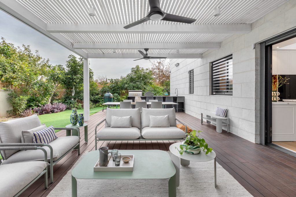 Covered outdoor seating facing the garden, with a sage-green coffee table