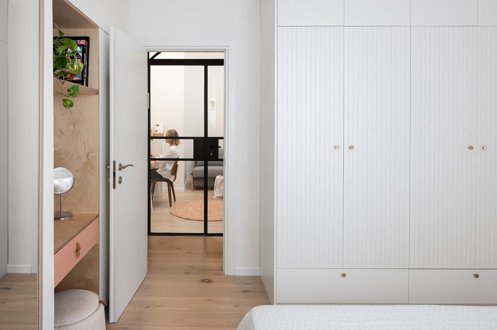 Bedroom with fluted white wardrobes and a view to the hallway