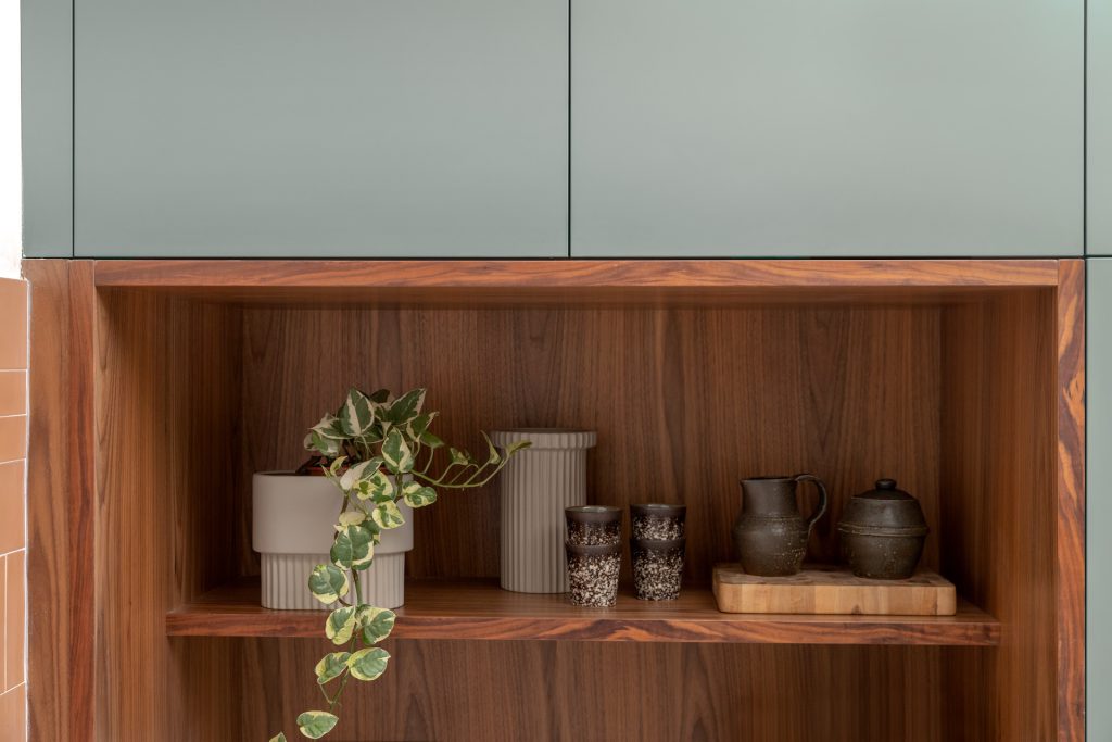 Detail: walnut niche with ceramics in green cabinetry
