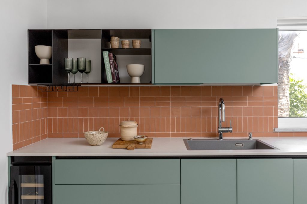 Terracotta tile backsplash and black shelves above the sink