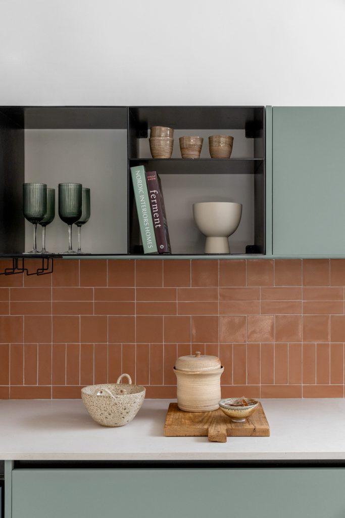 Detail: black metal shelf with tableware on terracotta tiles