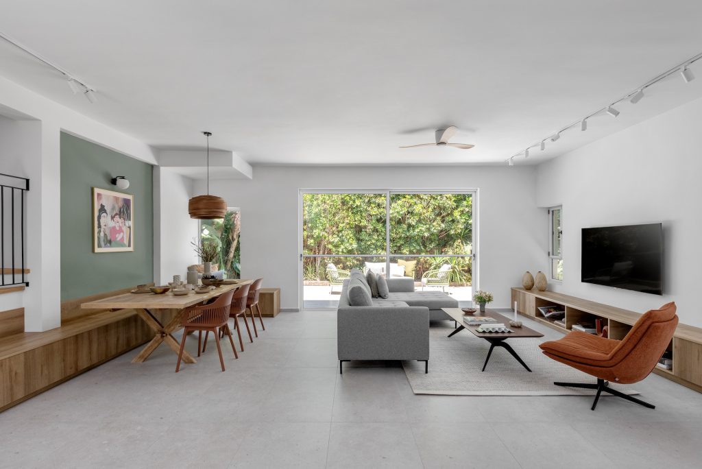 Open space with a grey sofa, a rust armchair and a dining area facing the garden