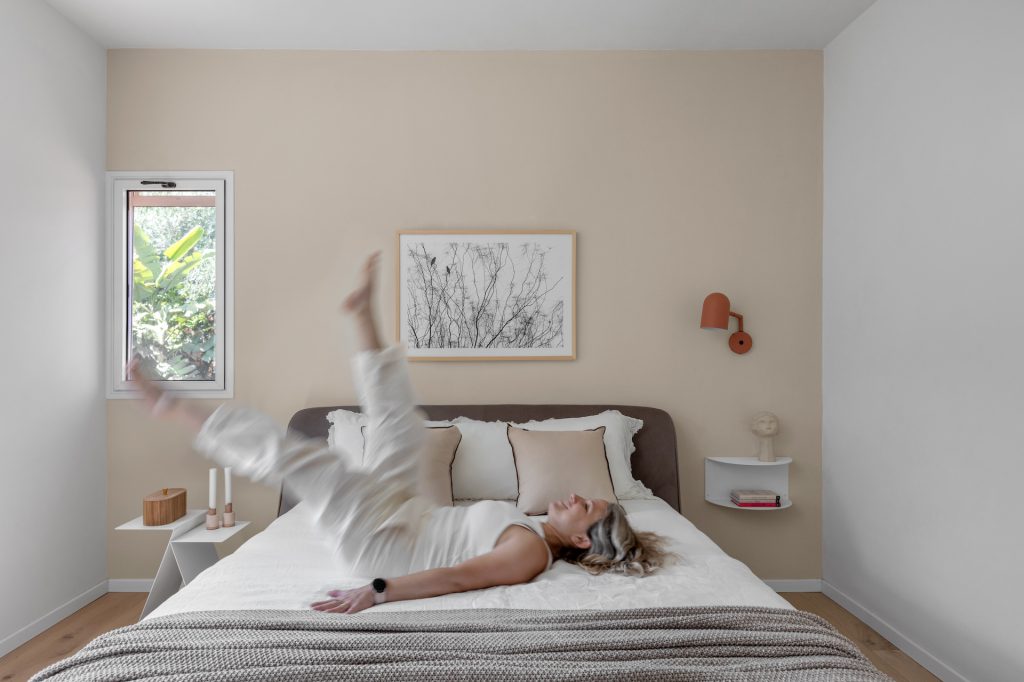 Double bed against a beige wall with an artwork