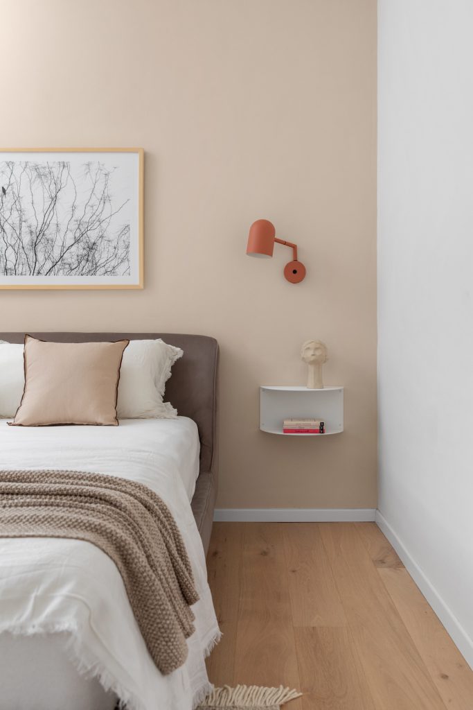 Rust wall lamp and a shelf beside the bed