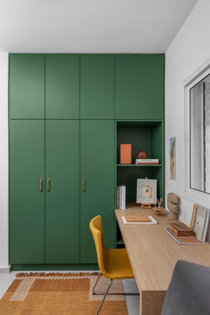Study with green wardrobes and a mustard chair