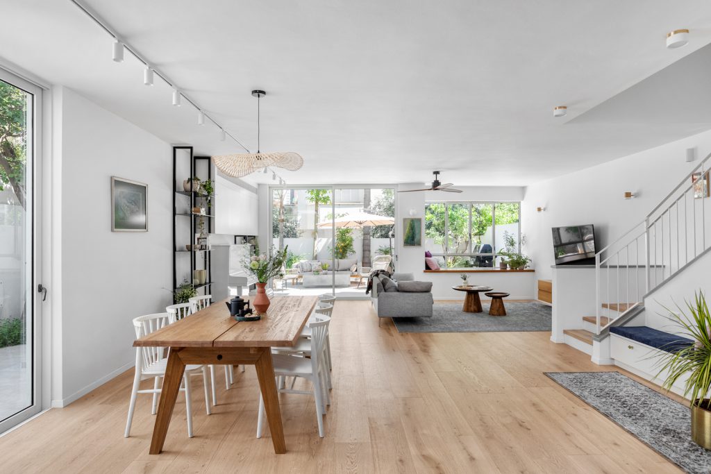 Wooden dining table with white chairs, looking to the living room