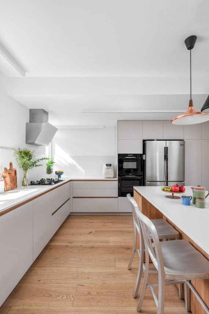 Long kitchen with a cabinet wall and a stainless fridge