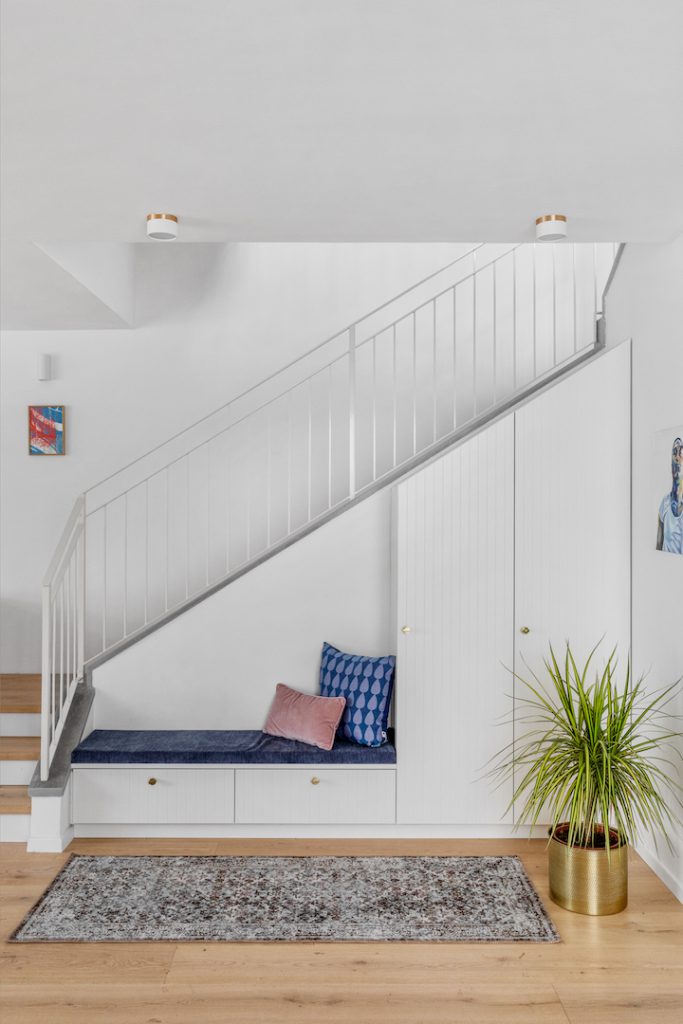 Upholstered bench under the stairs and a planter