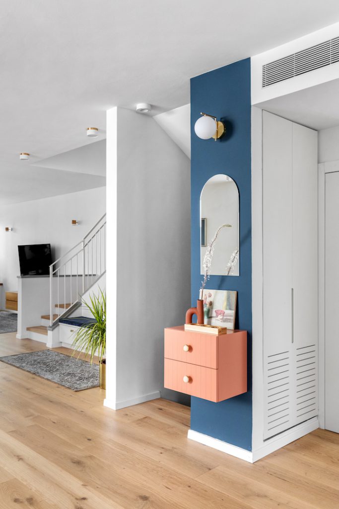 Blue column with a mirror and a peach wall-hung cabinet