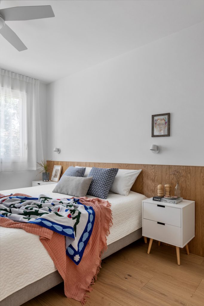 Bedroom with a wooden headboard and a colourful throw