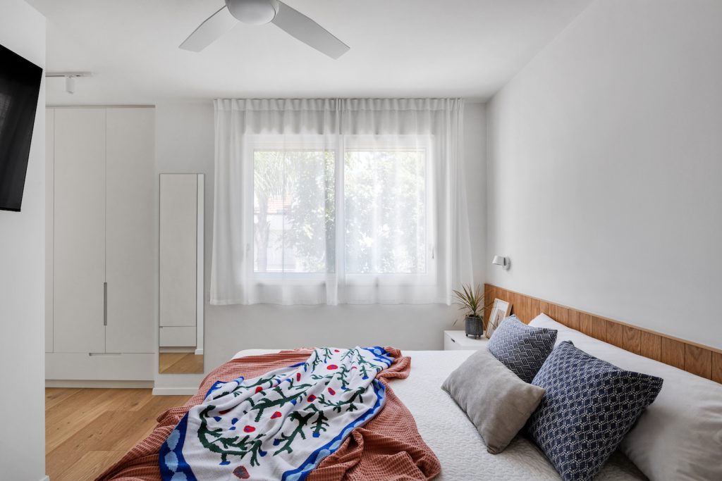 Double bed facing sheer curtains and a white wardrobe