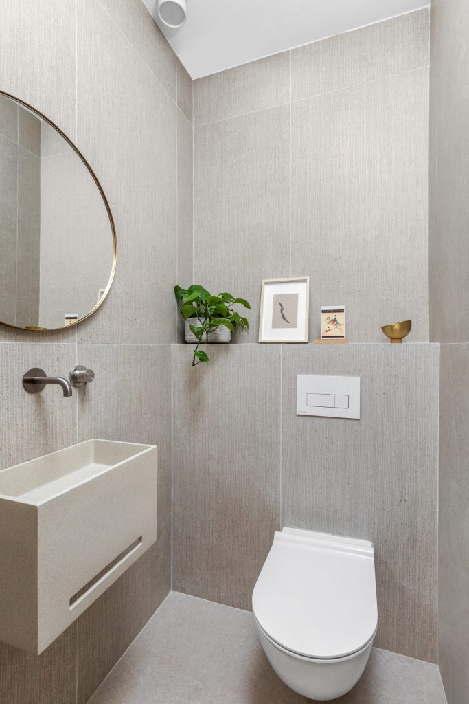 Guest toilet with a white wall-hung basin and an oval mirror