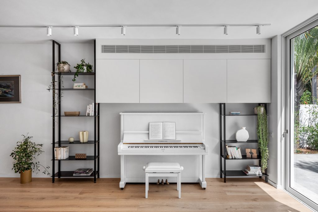 White piano between two black metal bookcases