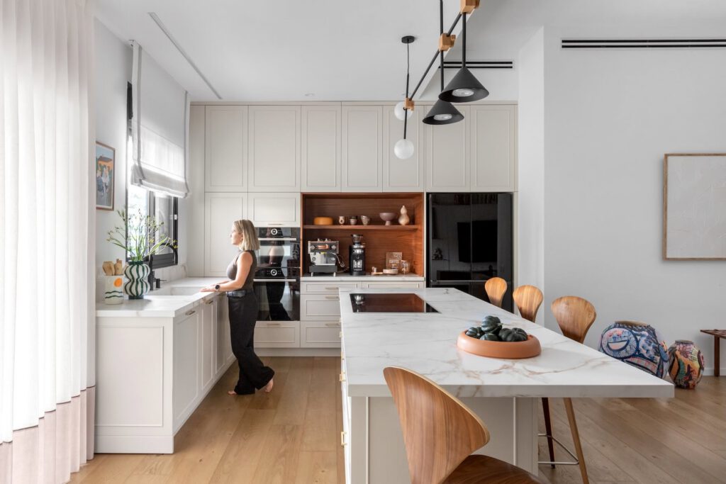 White kitchen with a marble island and black pendants, a project by Chen Shadmi, Shadmi Design