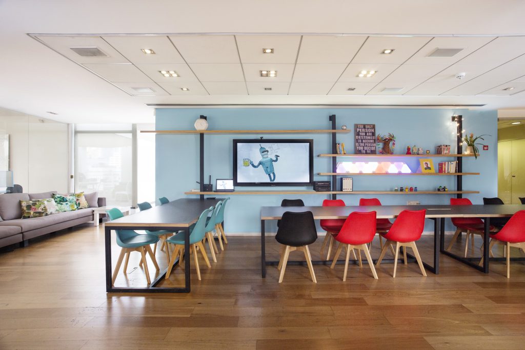 Open office with a light blue wall, desks and red and teal chairs, SafeBreach offices in Tel Aviv – Chen Shadmi, Shadmi Design
