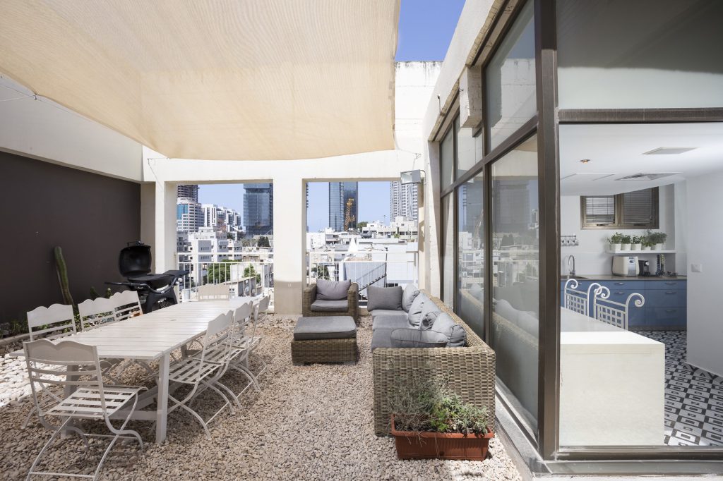Roof terrace with a long dining table and wicker sofas