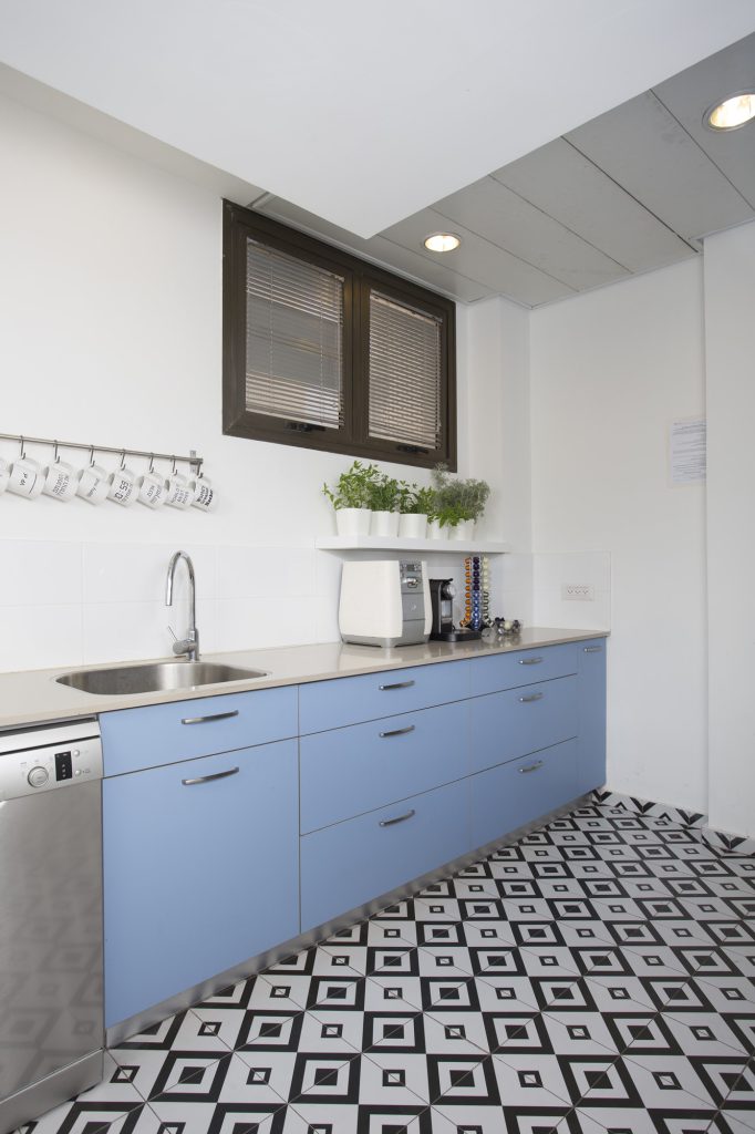 Light blue kitchenette on a black-and-white patterned floor