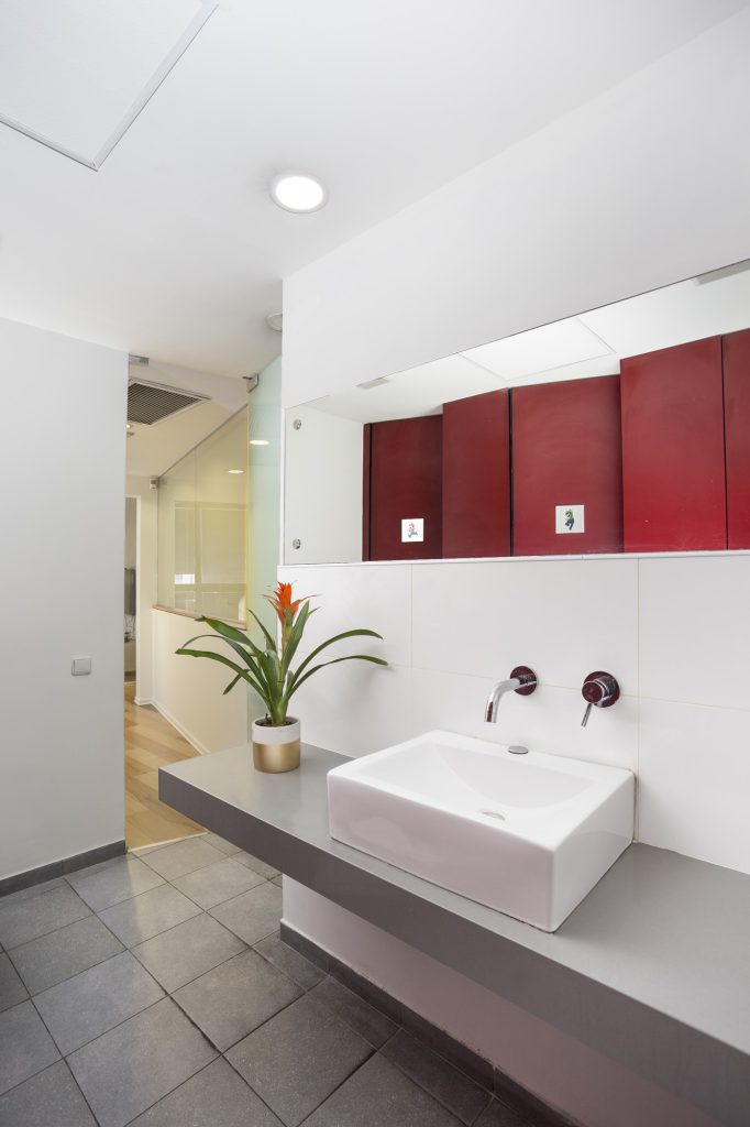 White basin on a grey counter with red cabinets