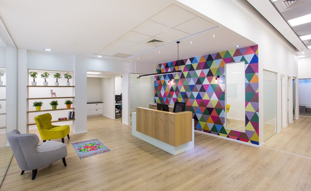 Reception desk in front of a colourful triangle wall with armchairs