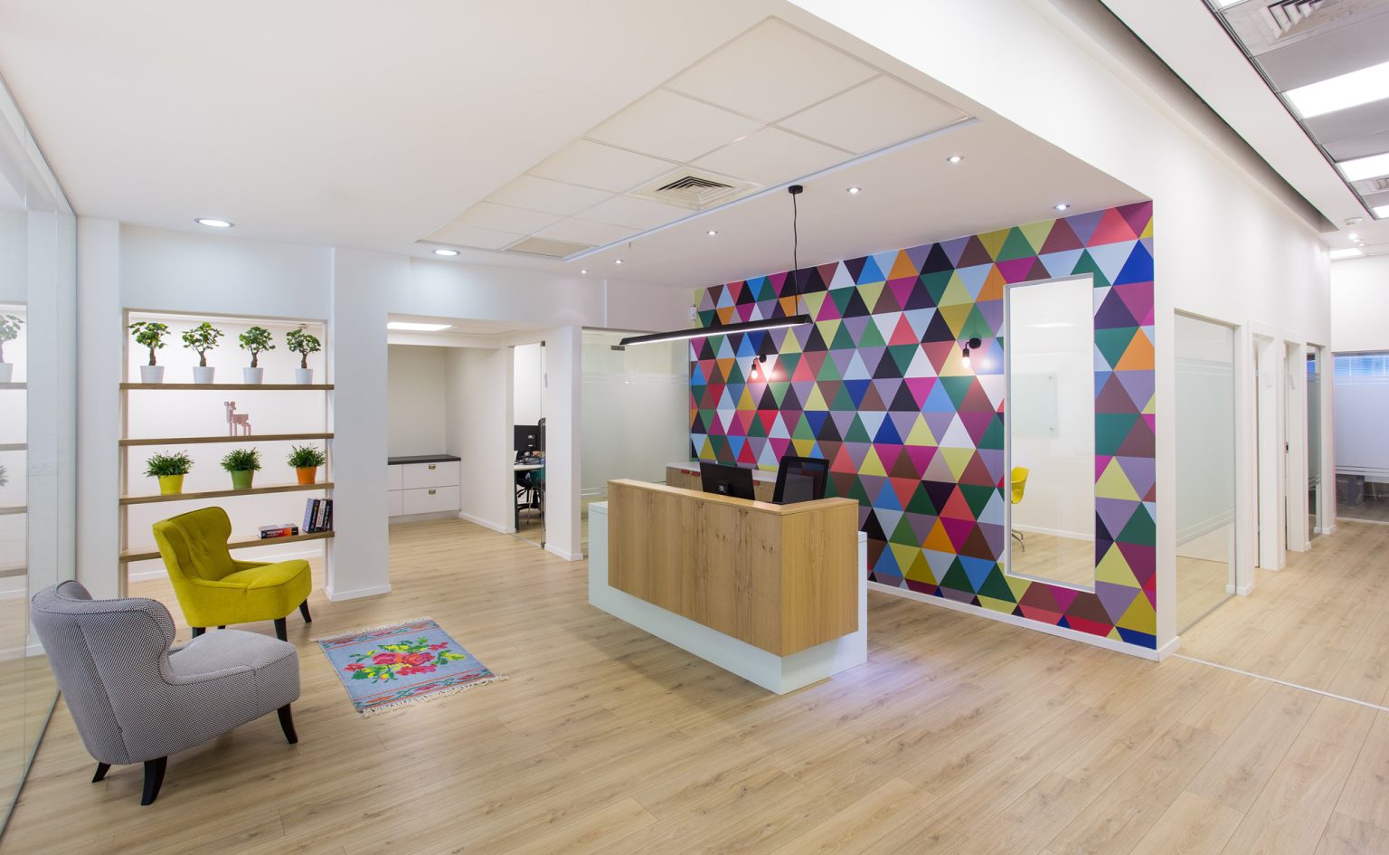 Reception desk in front of a colourful triangle wall with armchairs