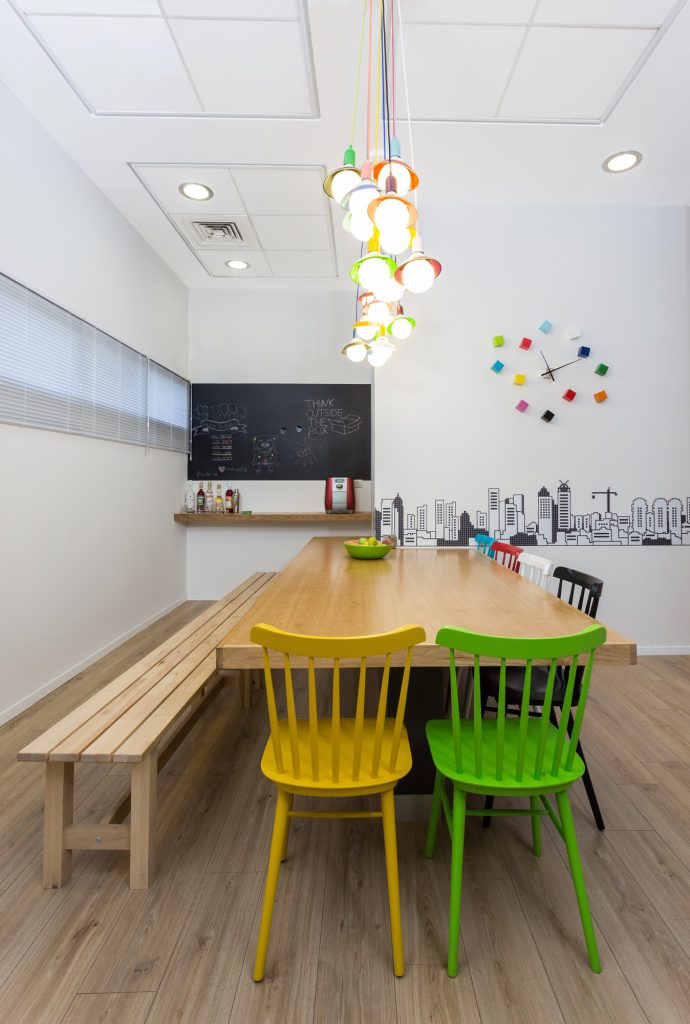 Wooden table with a bench and yellow and green chairs