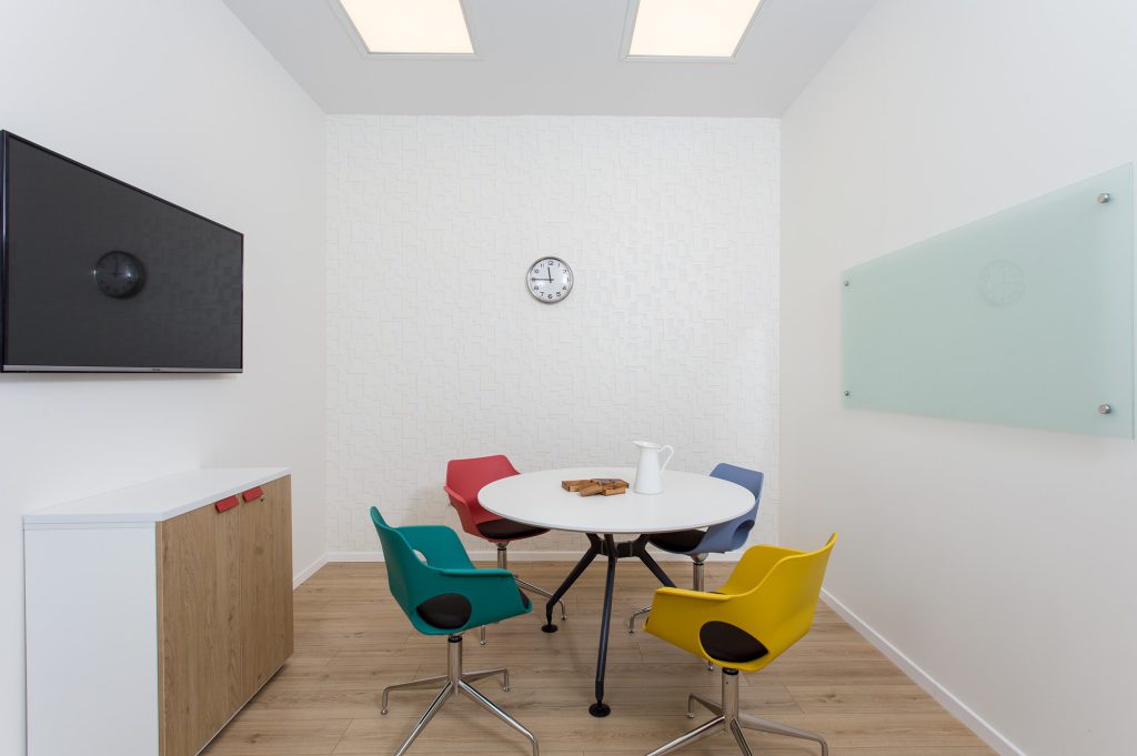 Meeting room with a white table and colourful chairs