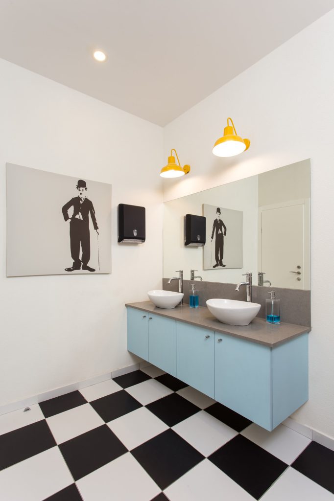 Two basins on a light blue cabinet with yellow lamps